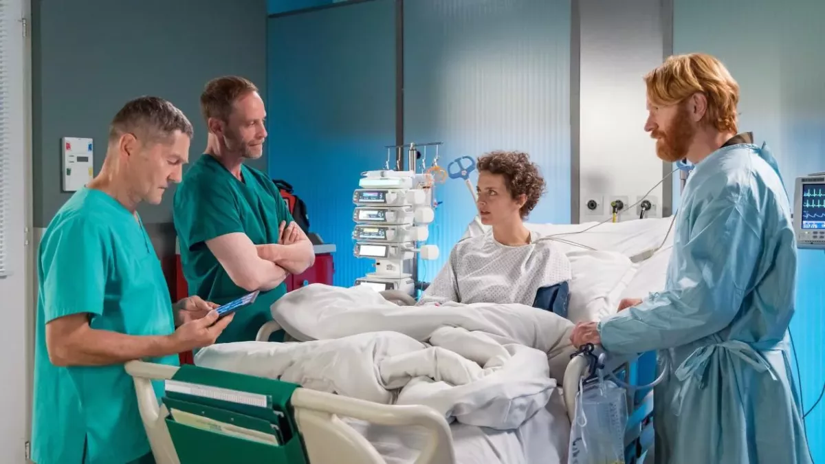 Dr. Hoffmann (Julian Weigend, 2.v.li.) und Dr. Kaminski (Udo Schenk, li.) haben keine guten Nachrichten für Kamela Szabo (Karoline Bär). Sie muss sofort operiert werden, sonst könnte sie beiden Nieren verlieren. Kamelas Mann Daniel (Volker Muthmann, re.) ist klar, dass das alles nicht passiert wäre, wenn Kamela eher zum Arzt gegangen wäre.