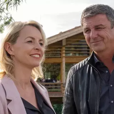 "Der Bergdoktor: Bittere Tränen": Martin (Hans Sigl) steht nah bei Franziska (Simone Hanselmann) vor einem Holzhaus und lächelt sie an.